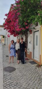 Three women standing under a pink bougainvillea arch in Portugal